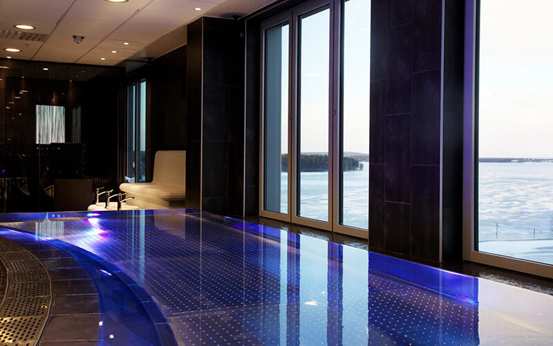 Ein Hotelpool mit Ausblick durch ein großes Fenster auf das Meer.