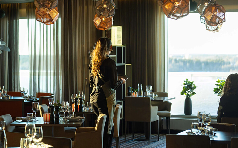 Eine Frau mit einem Tablett läuft durch ein Restaurant.