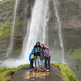 Familie unter einem Wasserfall in Regenjacken-