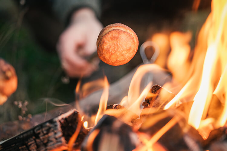 Ein Marshmallow wird an einem Stab über dem Feuer geröstet.