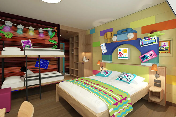 Familienzimmer mit Etagenbett, Doppelbett, bunten Wanddekorationen und Spielzeugautos auf einem Regal.