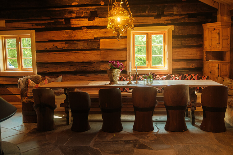 Ein großer Esstisch mit sechs Stühlen in einem Holzhaus. 