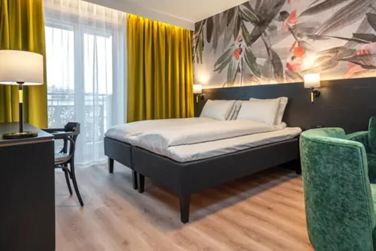 Ein Doppelbett in einem Hotelzimmer mit gelben Vorhängen.