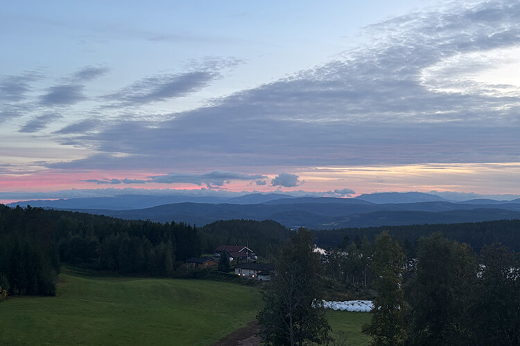 Eine weite Landschaft mit Bergen im Hintergrund bei Sonnenuntergang.