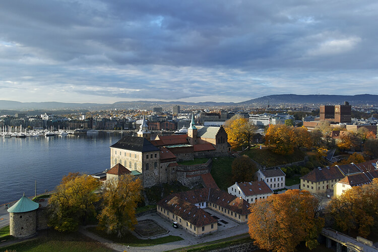Blick von oben auf Oslo. Man sieht bunte Bäume und Wasser.