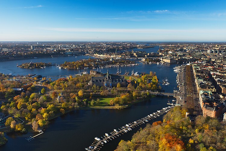 Luftaufnahme von Stockholm im Herbst mit Wasserflächen, herbstlich gefärbten Bäumen und Booten an Stegen