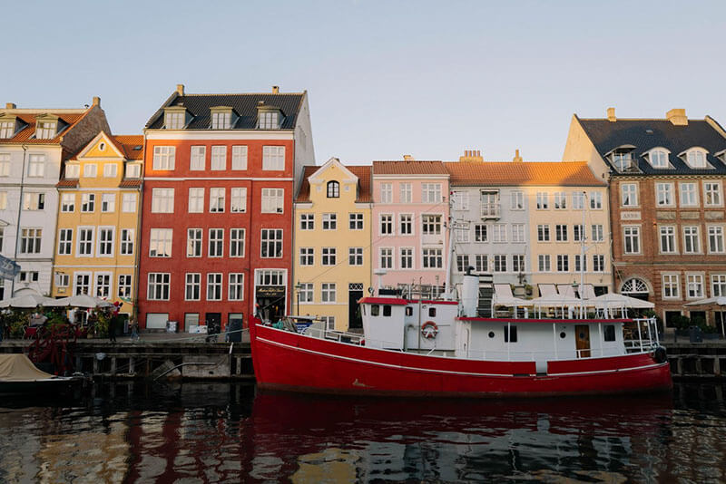 Mehrere bunte mehrstöckige Häuser am Wasser mit einem roten Boot im Vordergrund.